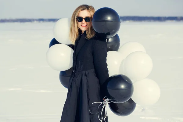 A woman with balloons is having fun in the winter on a snowy bac — Stock Photo, Image