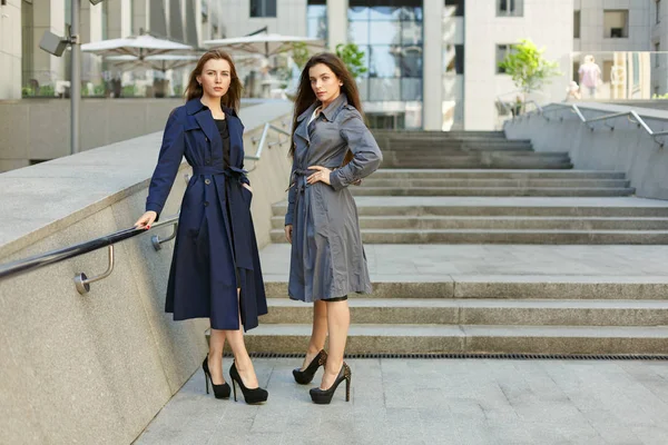 Two business women in coats are negotiating on the background of — Stock Photo, Image