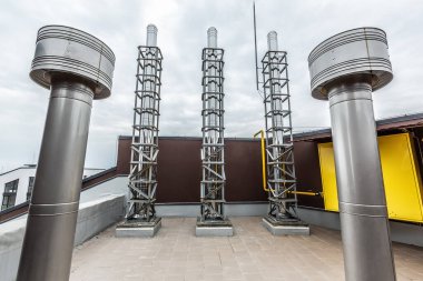 Bir binanın çatısındaki endüstriyel gaz kazanının bacaları ve havalandırma sistemi..