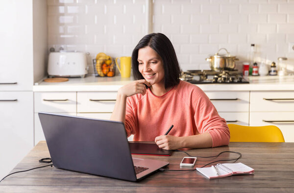 Woman works at home at the computer in quarantine, with a smile on her face