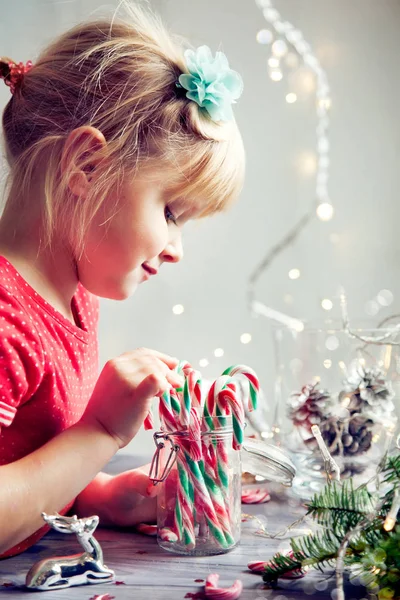 Bambina che gioca con decorazioni natalizie e caramelle — Foto Stock