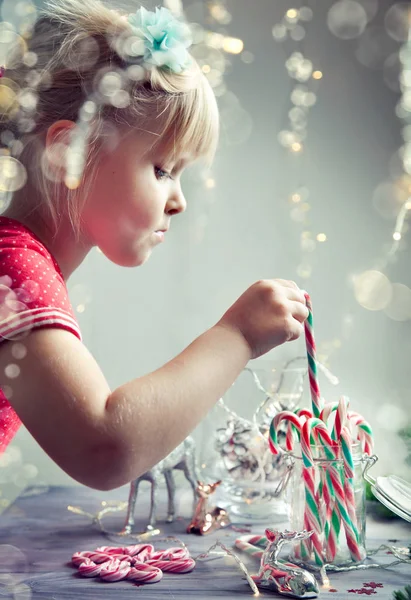 Niña jugando con decoraciones de Navidad y caramelos —  Fotos de Stock
