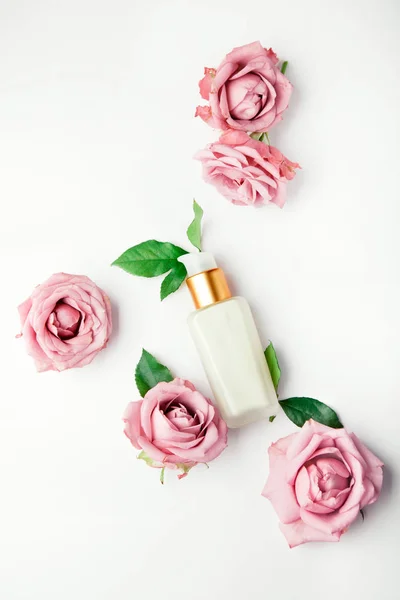 Crema viso / set di lozioni con rose rosa su bianco — Foto Stock