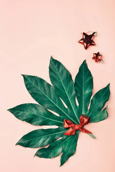 Пальмовые листья с рождественскими украшениями на розовом фоне с c — стоковое фото