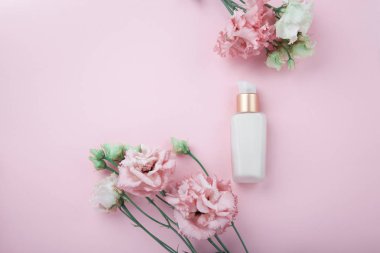 Yüz kremi taze pembe ve beyaz çiçekler ile flatlay pembe üzerinde