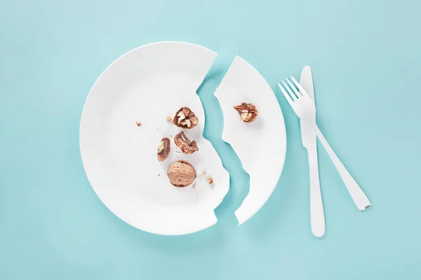 Plate broken in attempt to cut a nut with knife and fork — Stock Photo, Image