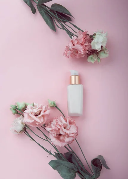 Gezichtscrème met verse roze en witte bloemen, flatlay op roze — Stockfoto