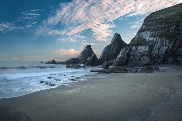 Impresionante puesta de sol colorido sobre el paisaje de playa con roca dentada f — Foto de Stock