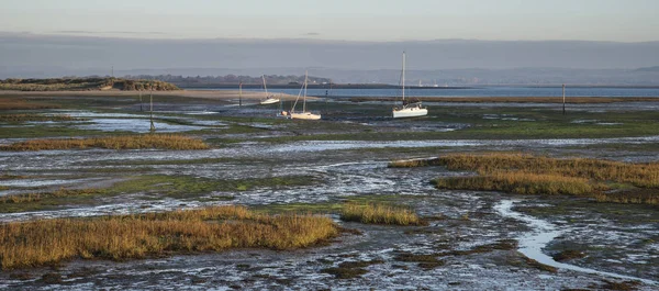 Boats in low tide mudflats of empty harbour at sunrise — Stock Photo, Image