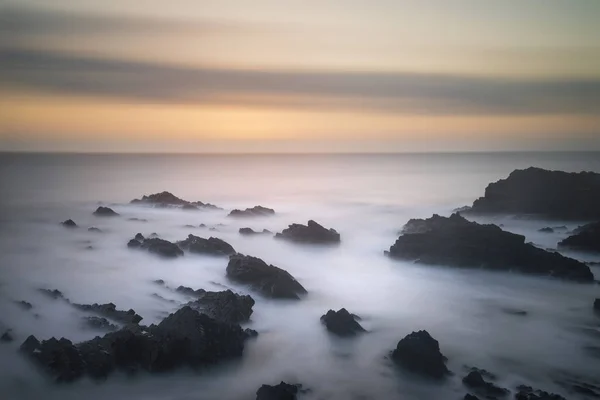 Beautiful long exposure landscape image of sea over rocks during — Stock Photo, Image