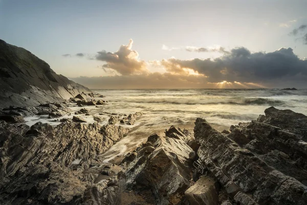 Krásné barevné zářivé slunce nad skalnatou pláž s dlouhým exp — Stock fotografie