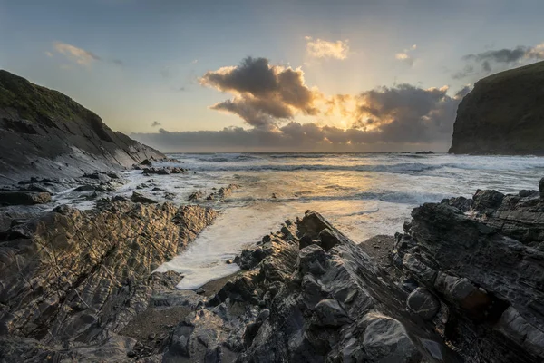 Hermosa puesta de sol vibrante colorido sobre la playa rocosa con exp largo —  Fotos de Stock