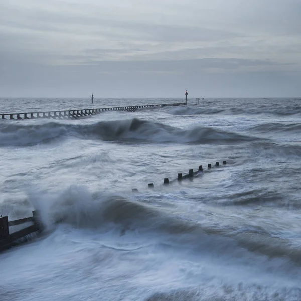 Beautiful dramatic stormy landscape image of waves crashing onto