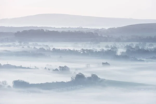 Splendido paesaggio rurale inglese nebbioso all'alba in inverno con — Foto Stock