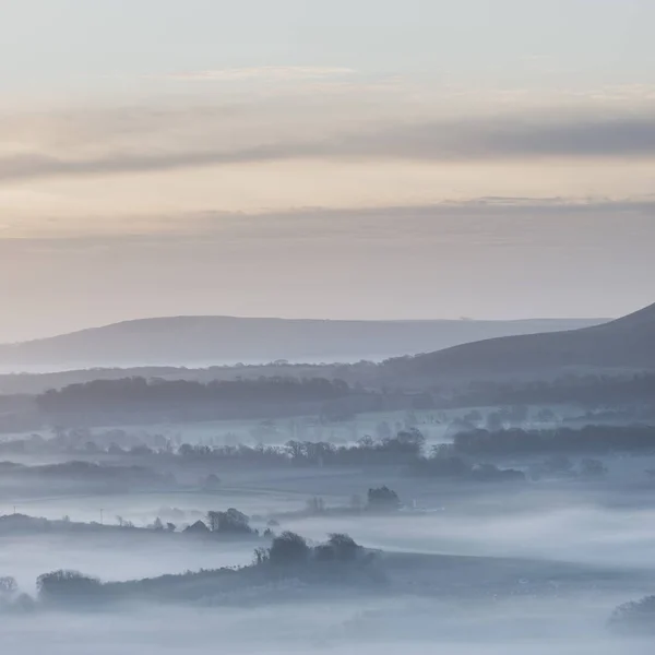 Stunning foggy English rural landscape at sunrise in Winter with — Stock Photo, Image