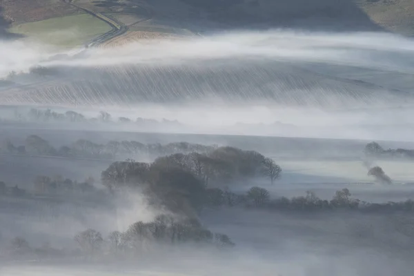 Stunning foggy English rural landscape at sunrise in Winter with — Stock Photo, Image