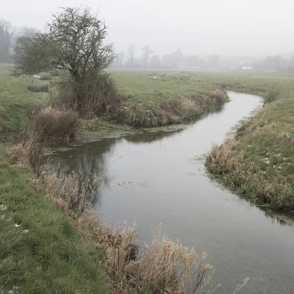 Cold misty Winter landscape over stream in English countryside — Stock Photo, Image