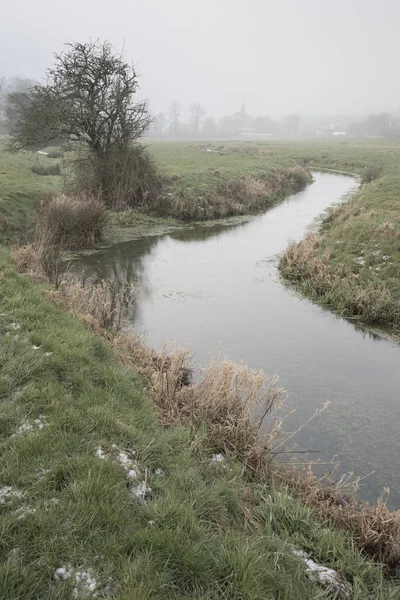 Cold misty Winter landscape over stream in English countryside — Stock Photo, Image
