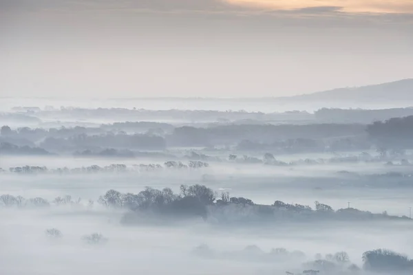 Stunning foggy English rural landscape at sunrise in Winter with — Stock Photo, Image