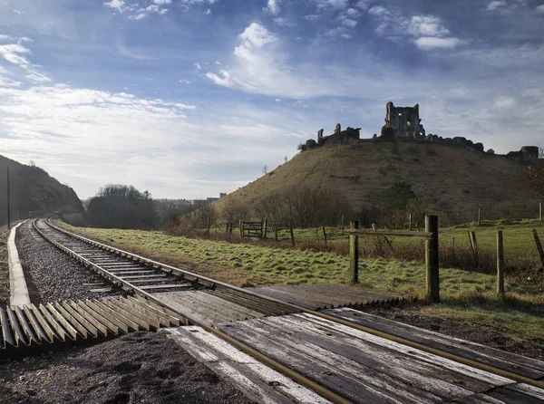 Railway runs around old Medieval castle ruins in countryside lan