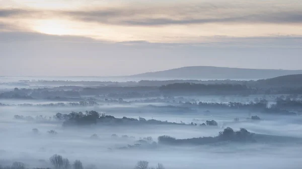 Stunning foggy English rural landscape at sunrise in Winter with — Stock Photo, Image