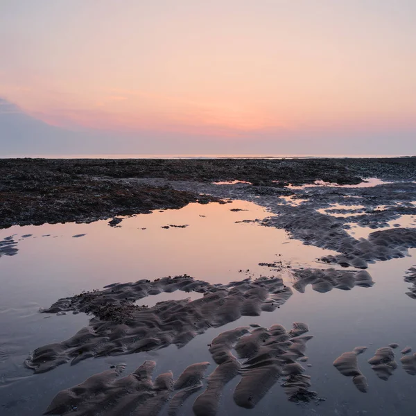 Hermoso amanecer colorido reflejado en piscinas de roca en marea baja o — Foto de Stock