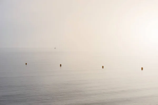 Minimalistické fine art obrázek bójí na moři během mlhavé ráno — Stock fotografie
