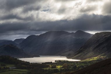 Majestic sun beams light up Crummock Water in epic Autumn Fall l clipart