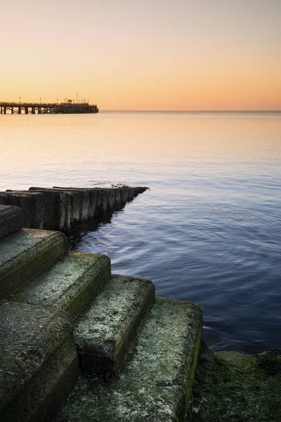 Stunning long exposure landscape image of orange sky over deep b — 스톡 사진