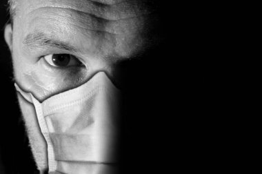 Coronavirus veya COVID-19 'dan korunmak için keskin gözlü, koyu ve karamsar erkek portresi.