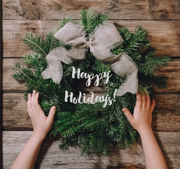 Hands of child spinning and decorating Christmas wreath — Stock Photo, Image