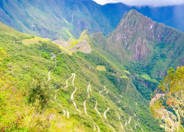 Peru 'daki Machu Picchu İnka bölgesi alışılmadık bir açıyla serpentin yolu ile sarp yeşil tepeye çıkıyor.