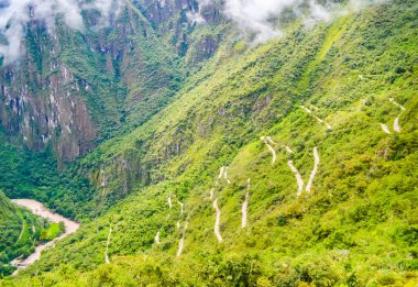 Peru 'daki Machu Picchu harabelerine giden yeşil ormanda sarp bir yılan yolu. Bulutlar ve güzel bir ışık. 