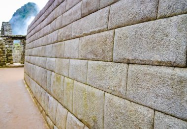 Machu Picchu antik duvarı. Arka planda sisli tepeler var.