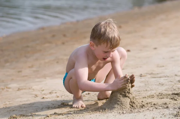 ビーチで小さな男の子が砂で遊ぶ — ストック写真
