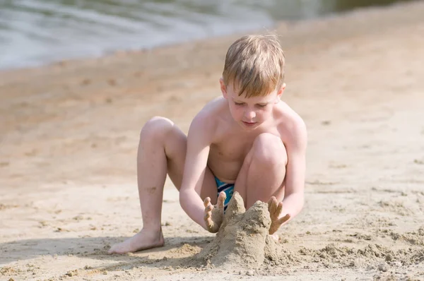 ビーチで小さな男の子が砂で遊ぶ — ストック写真