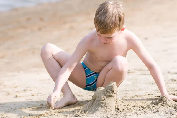 ビーチで小さな男の子が砂で遊ぶ — ストック写真