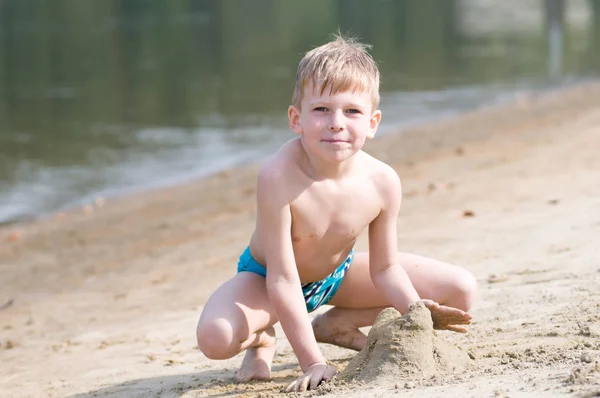 ビーチで小さな男の子が砂で遊ぶ — ストック写真