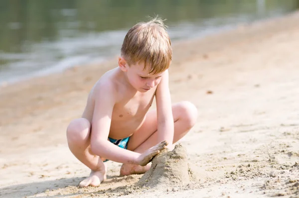 ビーチで小さな男の子が砂で遊ぶ — ストック写真