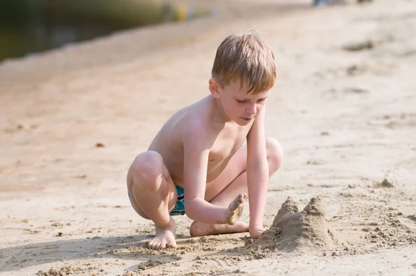 ビーチで小さな男の子が砂で遊ぶ — ストック写真