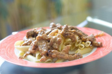 Beyaz plaka üzerinde penne makarna ile Sığır straganof