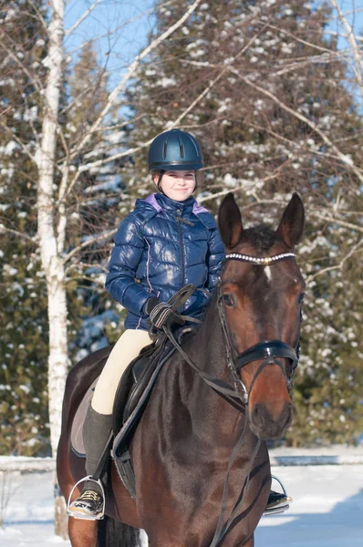 Десять лет девушки верхом на лошади зимой — стоковое фото