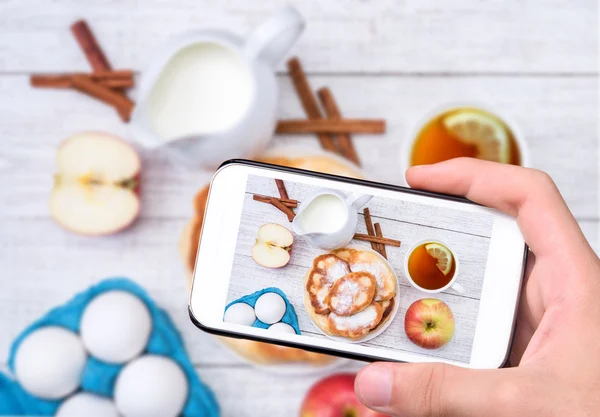 Handen nemen foto zelfgemaakte appel pannenkoeken met smartphone. — Stockfoto