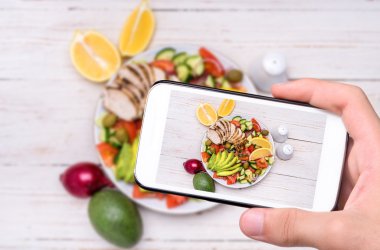 Eller fotoğraf Akdeniz tavuk salata avokado ile smartphone ile alarak.