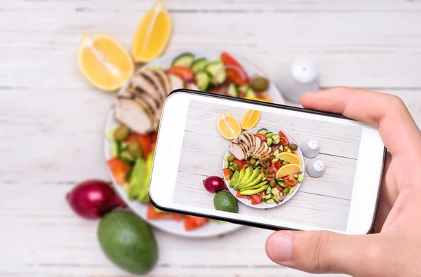 Mani scattare foto insalata di pollo mediterraneo con avocado con smartphone . — Foto Stock