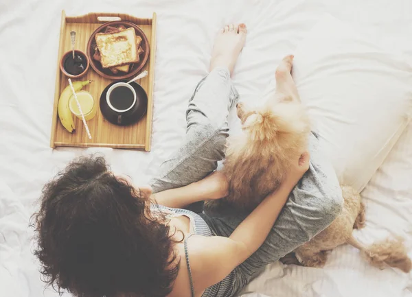 Jeune femme avec son chien dans un lit . — Photo