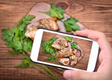 Eller fotoğraf pişmiş tavuk rulo kırmızı biber ile smartphone ile alarak.