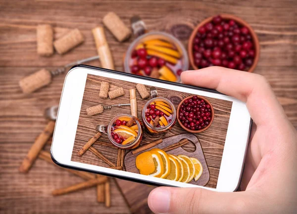 Eller fotoğraf ev yapımı mulled şarap portakal dilimleri, kızılcık, tarçın ile smartphone ile alarak.
