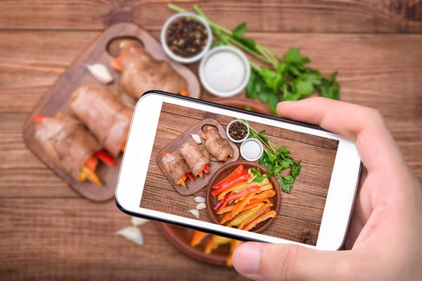 Mãos tirando fotos assadas rolos de frango com páprica com smartphone . — Fotografia de Stock