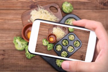 Ellerini alarak yumurta muffins brokoli fotoğraf ve smartphone ile peynir.